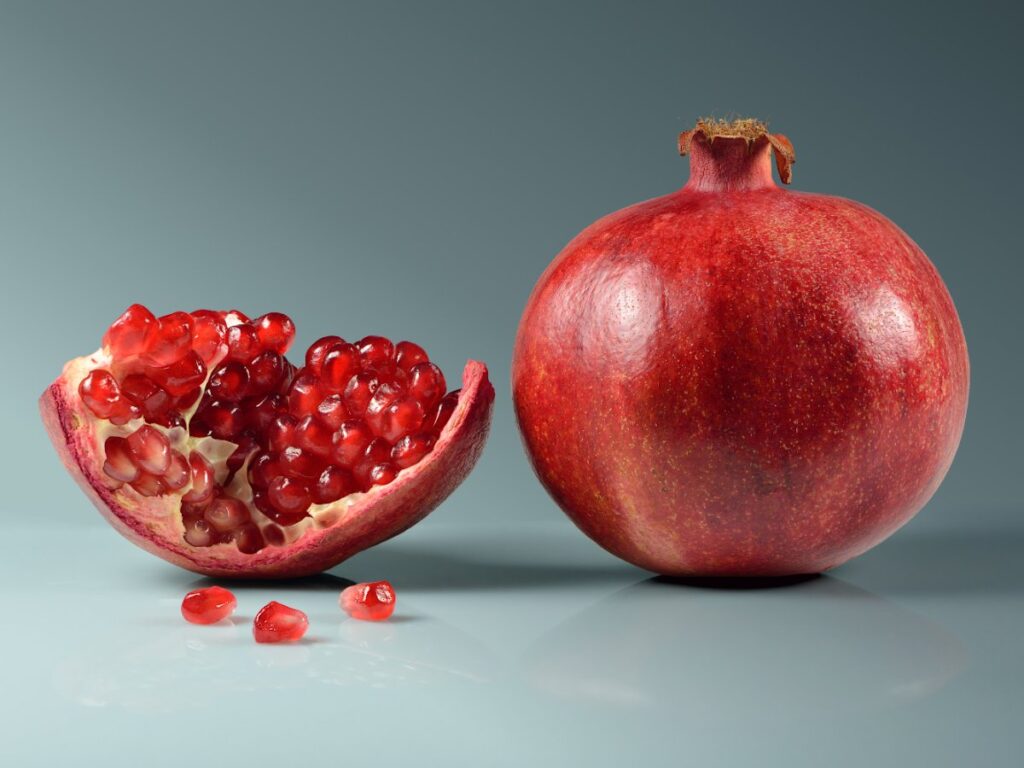 Pomegranate fruit whole and opened showing red arils